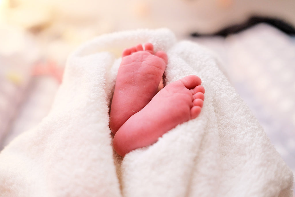 newborn feet peeking out of blanket