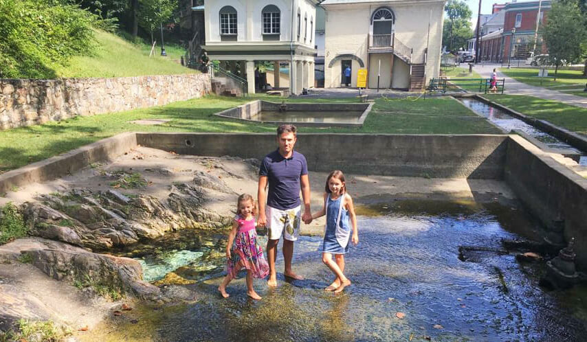 Michal and daughters playing in water outside their home