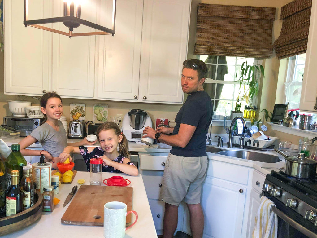 Michal cooking in their home kitchen with his two daughters